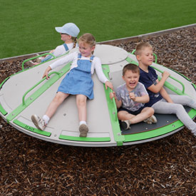 Kids playing on the inclusive roundabout at a playground